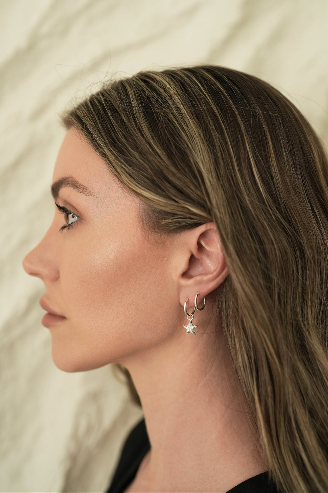 Founder of Nusands Emily Micari side profile wearing sterling silver round hoop earring with removable star charms.