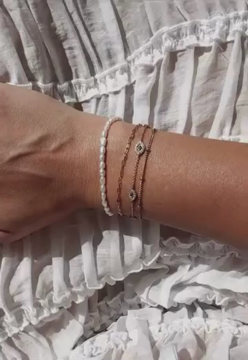 Woman wearing the pearl bracelet on a white dress showing it worn with other bracelets
