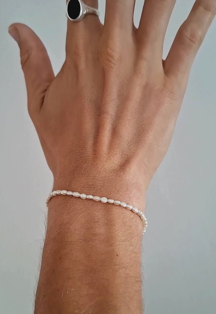 Male wearing the pearl bracelet with a netural background