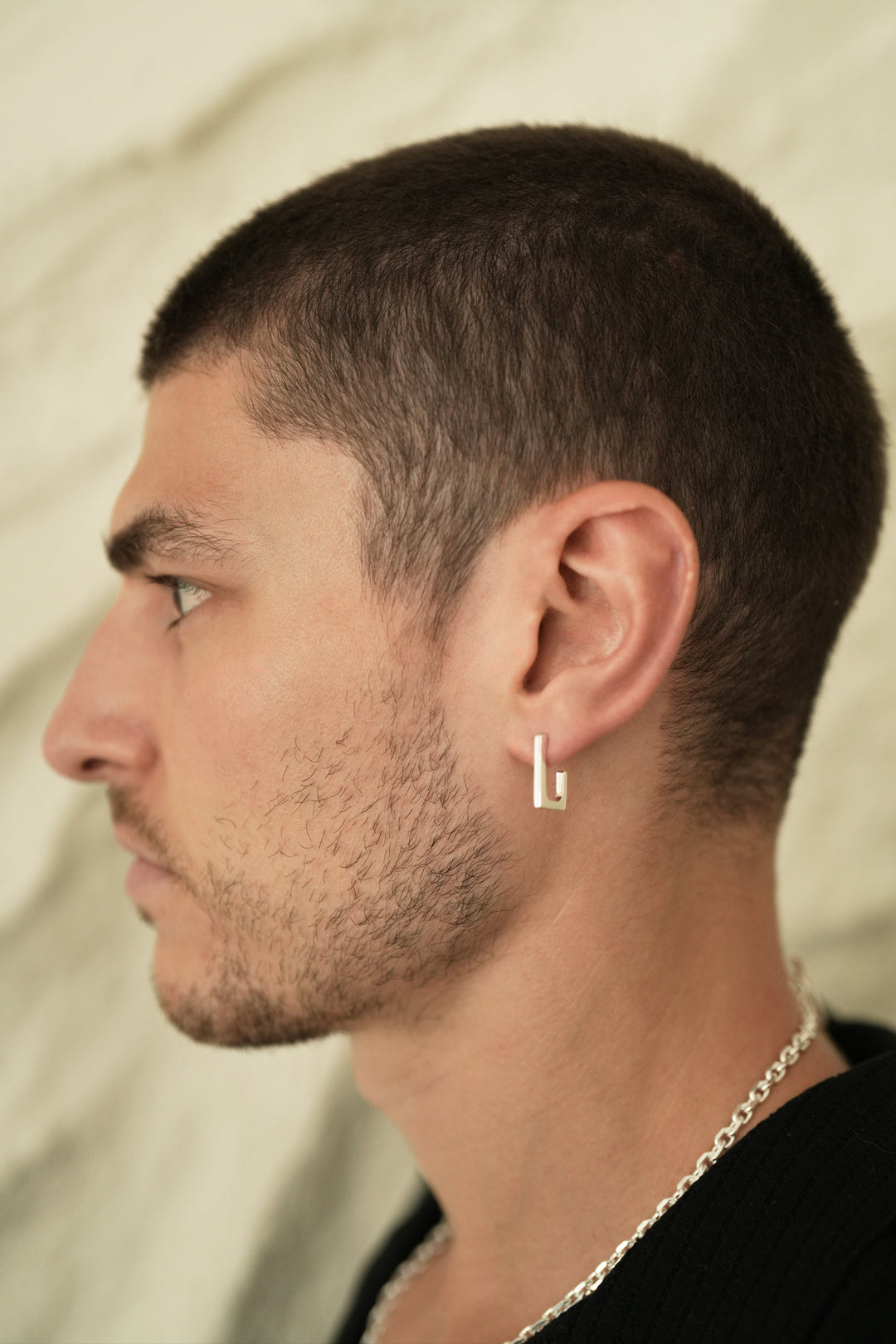 Founder of Nusands Corey Micari side profile wearing sterling silver rectangle earring in left ear