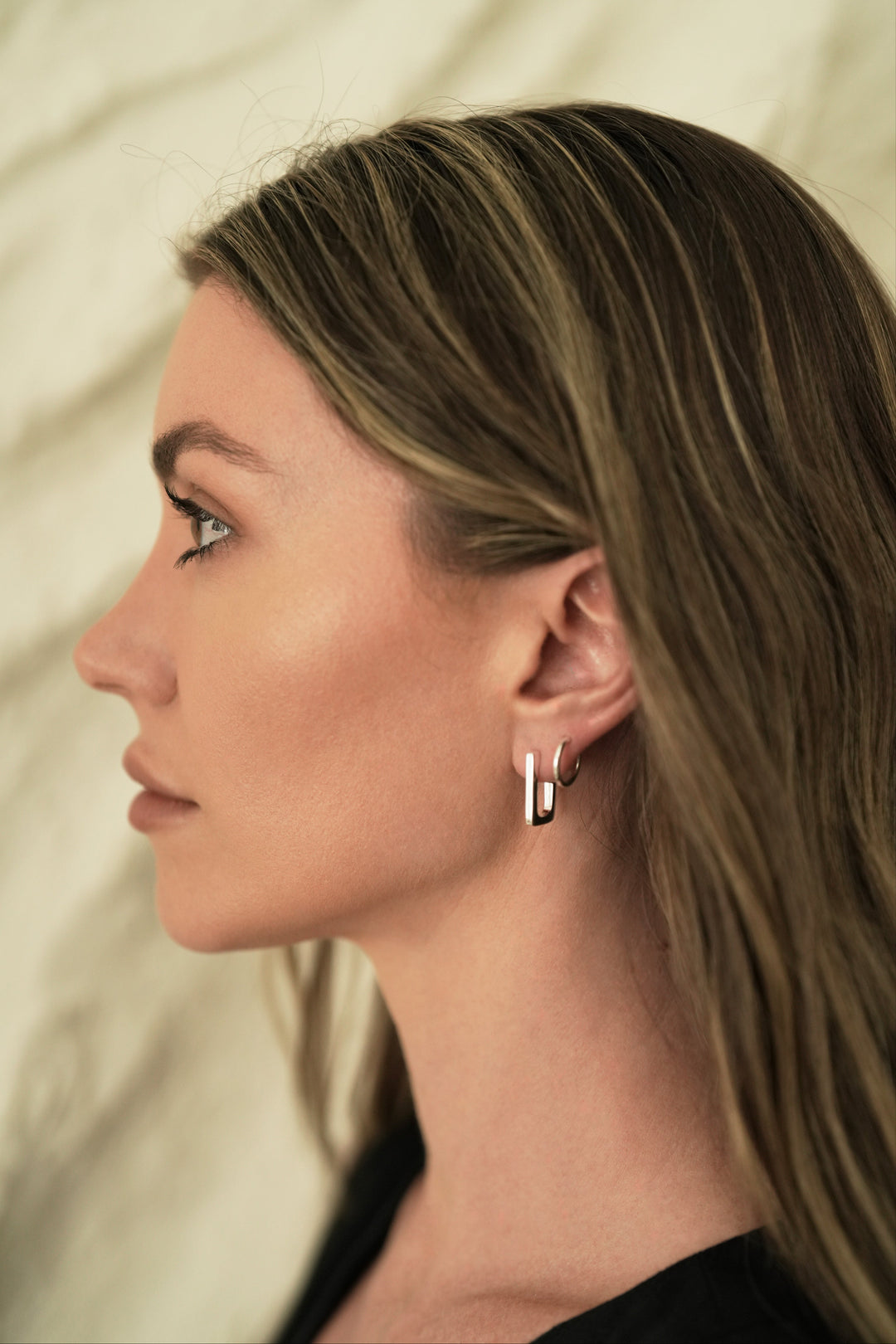 Founder of Nusands Emily Micari side profile wearing sterling silver rectangle earring in left ear